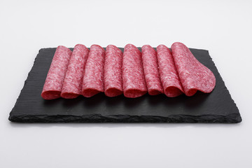 delicious sliced salami on a stone plate white background