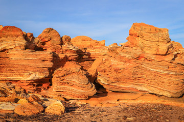 Red rocky cliffs on coastline with blue sky