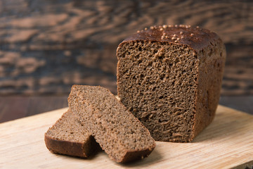 Black rye bread with coriander on a wooden background