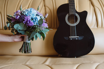 Wedding details.  guitar and the bouquet are on a leather sofa