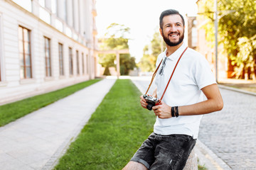 Stylish hipster with a beard and a camera, walking around the city with a camera