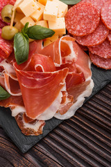 Cold smoked meat plate on a rustic wooden background