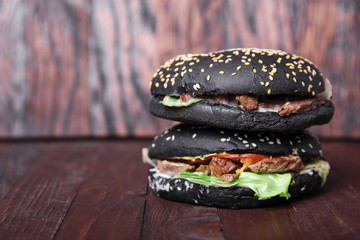 Delicious double black burger with juicy beef on a wooden background