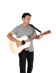 A tall man standing with his guitar and playing