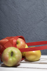 Ripe aromatic apples in a wicker basket. Located on a wooden box, knocked out of the boards.
