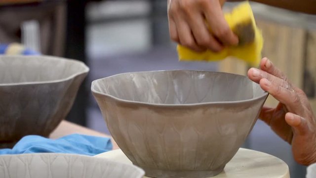 traditional pottery making, close up of potter's hands shaping a bowl on the spinning by clay