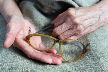 Broken glasses in the hands of an old woman.