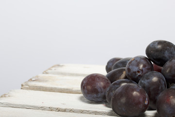 Ripe aromatic plums. Located on a wooden box, knocked out of the boards.