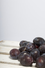 Ripe aromatic plums. Located on a wooden box, knocked out of the boards.
