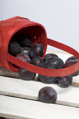 Ripe fragrant plums crumbled out of a wicker basket. Located on a wooden box, knocked out of the boards.
