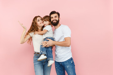 A happy family on pink studio background. The father, mother and son posing together