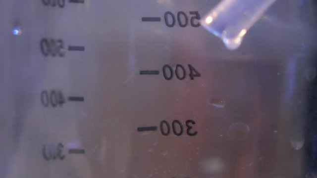 Drops of liquid from a plastic tube into the measuring liquid during the production of alcohol at home