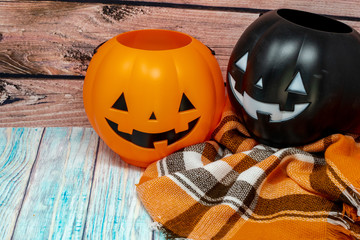 Orange and black jack o lantern trick or treat buckets , on a plaid blanket. Wooden background,...