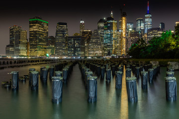 Fototapeta na wymiar Long time exposure of New York City Manhattan downtown skyline at night viewed from Brooklyn Bridge park