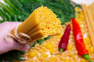 man hand holding Spaghetti and pipe rigate, cavatappi, herbs, garlic, pepper and tomatoes on...