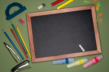 School concept. Empty chalk board, stationery on green background, copy space.