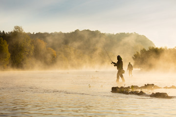Fishermen holding fishing rod, standing in river