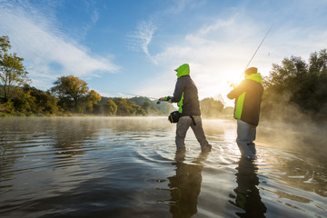 Fischer mit Angelrute, stehend im Fluss