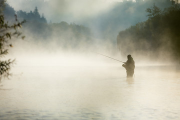 Fisherman holding fishing rod, standing in river