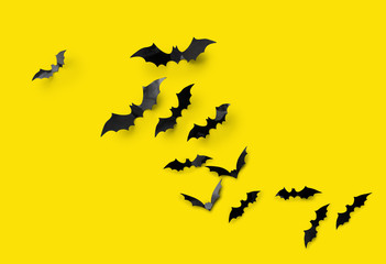 halloween decorations concept - many black paper bats on yellow background