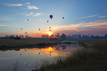 Hot air balloons rising into sky with sunrise