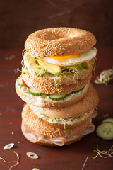variety of sandwiches on bagels: egg, avocado, ham, tomato, soft cheese, alfalfa sprouts