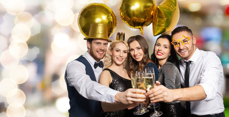 celebration, luxury and holidays concept - happy friends with golden party props clinking champagne glasses over festive lights background