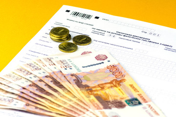 Russian annual tax Declaration of taxes of individuals. The Form 3-NDFL. A few Russian notes and coins are on the sheet of the Declaration.