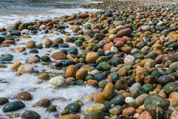 Wet, colorful, big pebbles on Mediterranean beach. Texture, background concept.