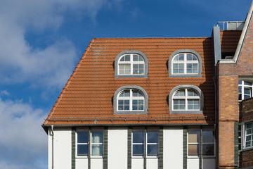 Fototapeta na wymiar red tiled roof with windows - blue sky