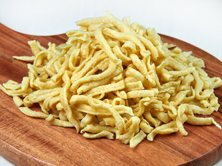 A heap of fresh Swabian dried egg noodles (spaetzle) on a wooden board