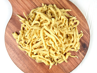 A heap of fresh Swabian dried egg noodles (spaetzle) on a wooden board