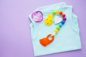 Baby yellow booties. Children's shoes and toys on purple background. Newborn.