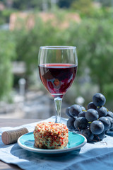 One wine glass with red wine served with red grape and soft goar cheese on outdoor terrace