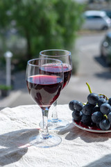 Two wine glasses with red wine served with red grape on outdoor terrace