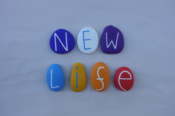 New Life text with colored stones letters over white sand