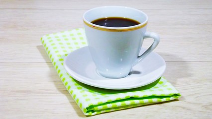 A Cup of fragrant tea and a green napkin on a wooden background.