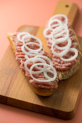 Schweine Mettbrötchen mit Zwiebeln auf Holzbrett