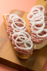Schweinemett Brötchen mit Zwiebeln auf Holzbrett