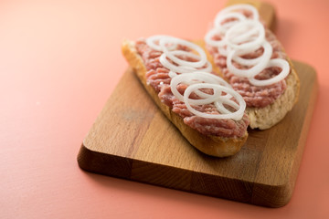 Schweine Mettbrötchen mit Zwiebeln auf Holzbrett