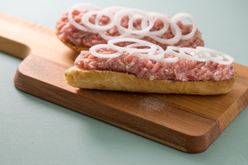 Schweinemett Brötchen mit Zwiebeln auf Holzbrett