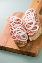 Schweine Mettbrötchen mit Zwiebeln auf Holzbrett