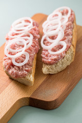Schweinemett Brötchen mit Zwiebeln auf Holzbrett