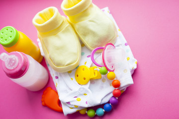 Baby yellow booties. Children's shoes and toys on pink background. Newborn.