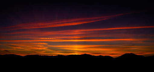 Beautiful autumn sunset landscape with a lot of colors like red, purple, orange, yellow, blue... and the mountains silhouettes