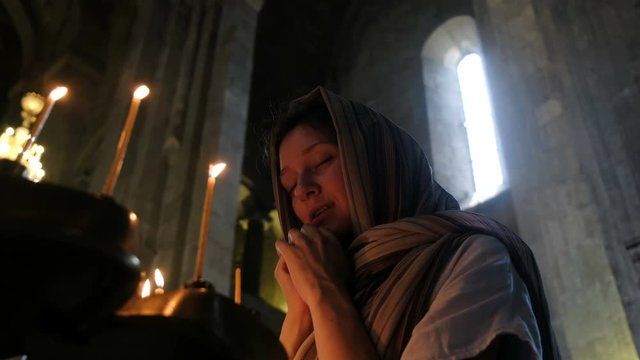 Woman in a headscarf praying before an icon in the Orthodox Catholic Church