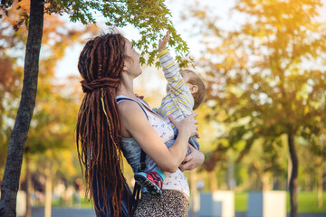 Modern happy mom with baby son walking in Sunny Park. Joy of motherhood and autumn mood