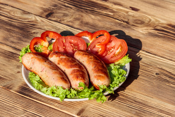 Grilled sausages with fresh vegetables on wooden table