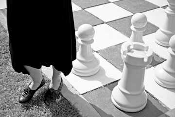 A women standing on the edge of a large outdoor chessboard. Standing on the fringe of society...