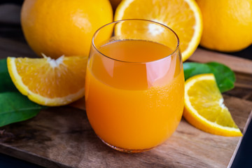 Glass of orange juice with fresh fruits on wooden floor
